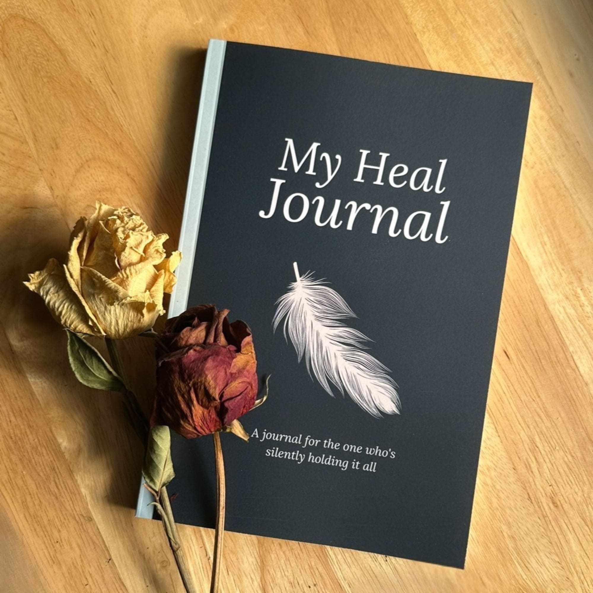 My Heal Journal physical guided healing journal cover with dried roses on wooden surface